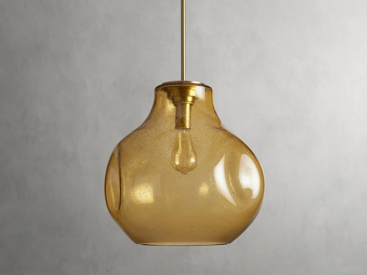 Organic 16" Pendant with amber mouth-blown glass shade, spherical shape, visible bulb inside, hanging by a rod.