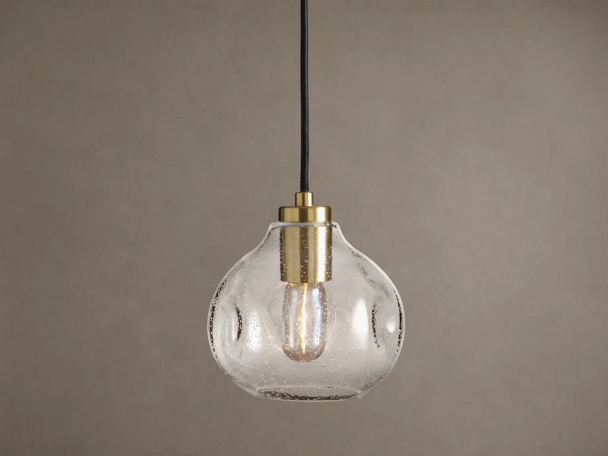 Organic 8" Pendant: Clear, seeded mouth-blown glass shade with brass hardware, black cord, and a glowing Edison bulb.