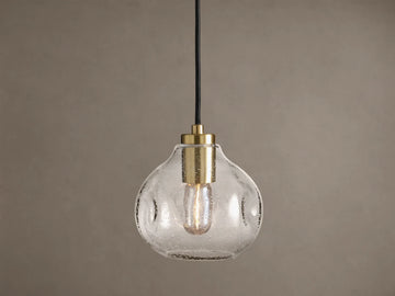 Organic 8" Pendant: Clear, seeded mouth-blown glass shade with brass hardware, black cord, and a glowing Edison bulb.
