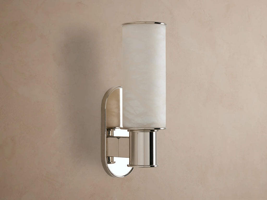 Harlin Sconce: vertical glowing alabaster cylinder, polished nickel racetrack backplate and base, mounted on a neutral wall.