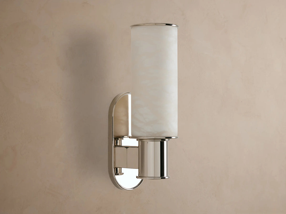 Harlin Sconce: vertical glowing alabaster cylinder, polished nickel racetrack backplate and base, mounted on a neutral wall.