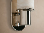Vertical Harlin Sconce with cylindrical white marbled alabaster cloche and polished nickel base mounted on a beige wall.