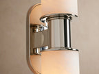 Harlin Double Sconce with two cylindrical white alabaster shades, polished nickel central support & oval backplate, on a beige wall.
