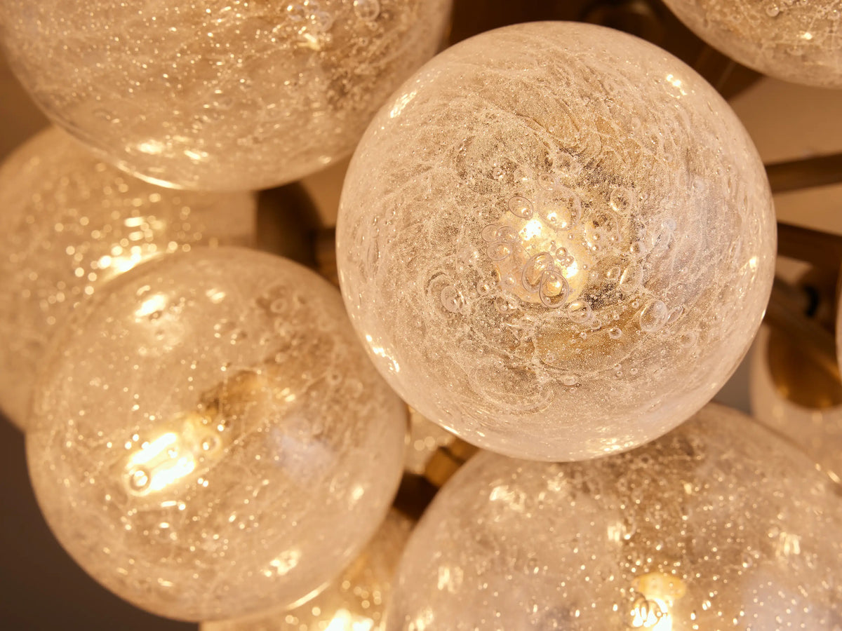 Mandoza Flush Mount with a burnished brass base and multiple textured glass globes, mounted on a light ceiling.