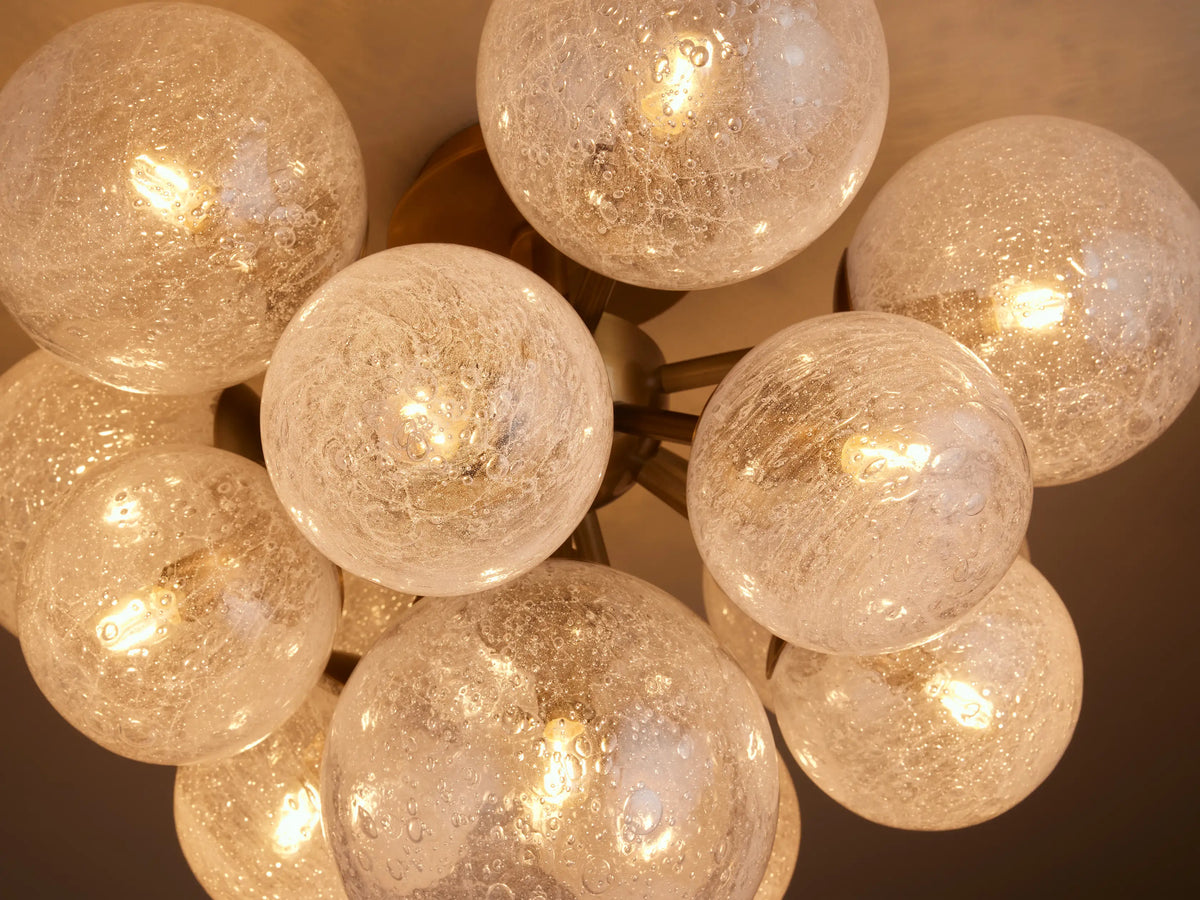 Close-up of Mandoza Flush Mount's artisanal, textured glass globes with warm, glowing LED bulbs inside.