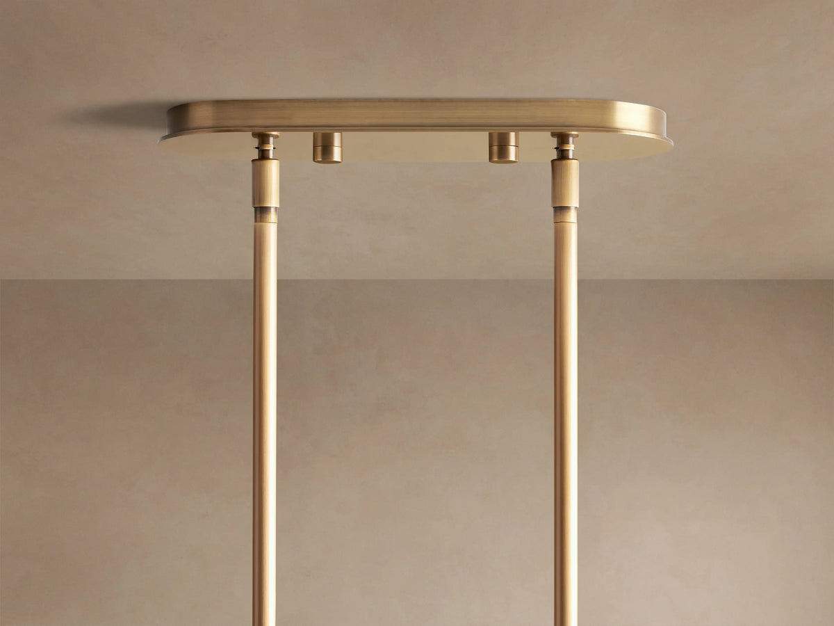 Mandoza Linear Chandelier: Close-up of clear, bubble-filled glass globes emitting warm light, connected by burnished brass metal.
