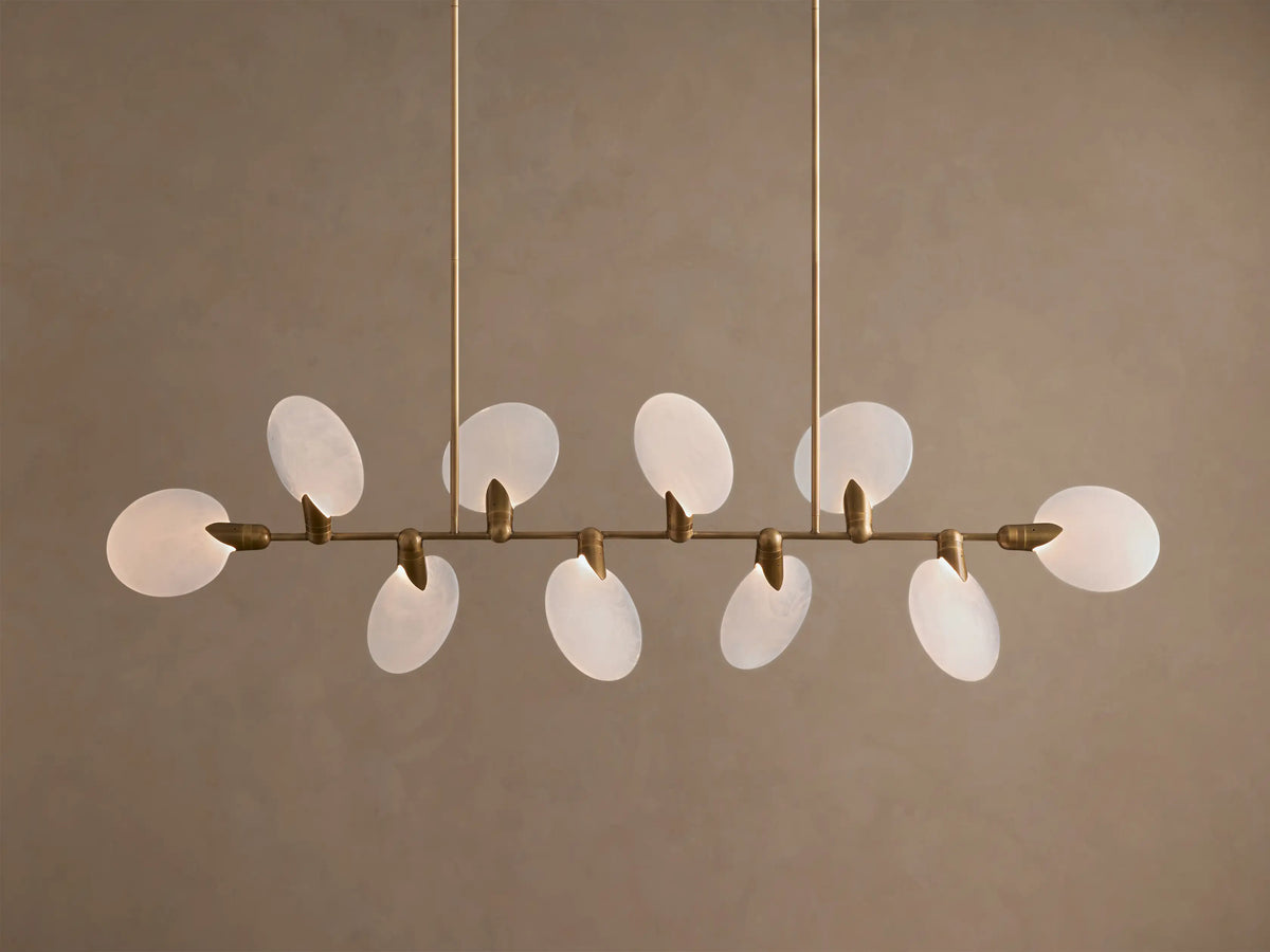 Lyla Linear Chandelier, 8 glowing frosted glass oval shades on a horizontal antique brass bar, suspended from above.