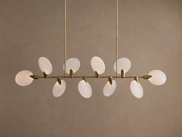Lyla Linear Chandelier, 8 glowing frosted glass oval shades on a horizontal antique brass bar, suspended from above.