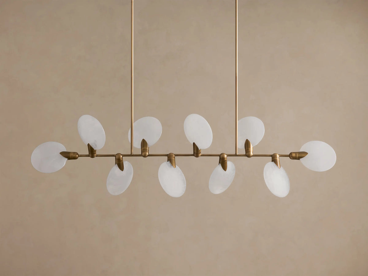 Lyla Linear Chandelier, 8 glowing frosted glass oval shades on a horizontal antique brass bar, suspended from above.