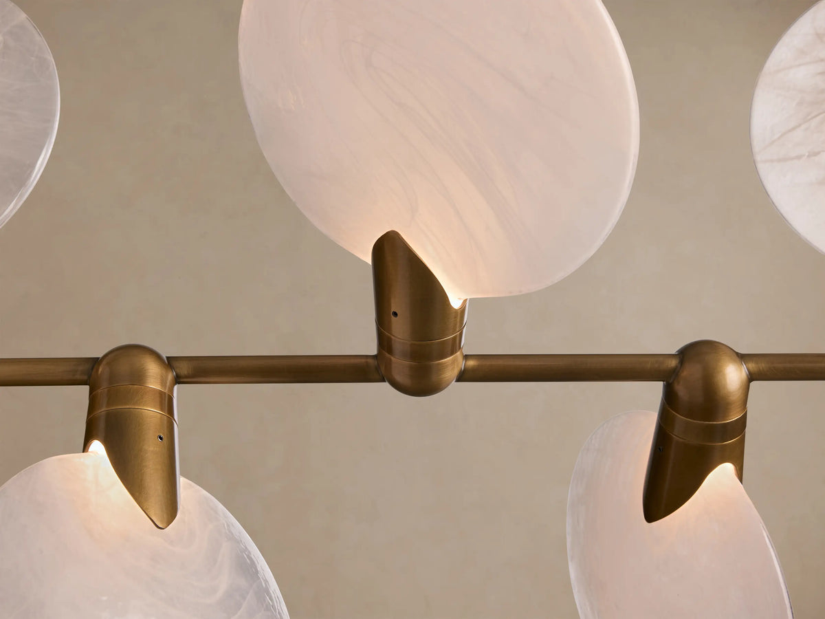 Lyla Linear Chandelier: Eight white oval frosted glass shades attached to a brass horizontal bar, suspended from above.