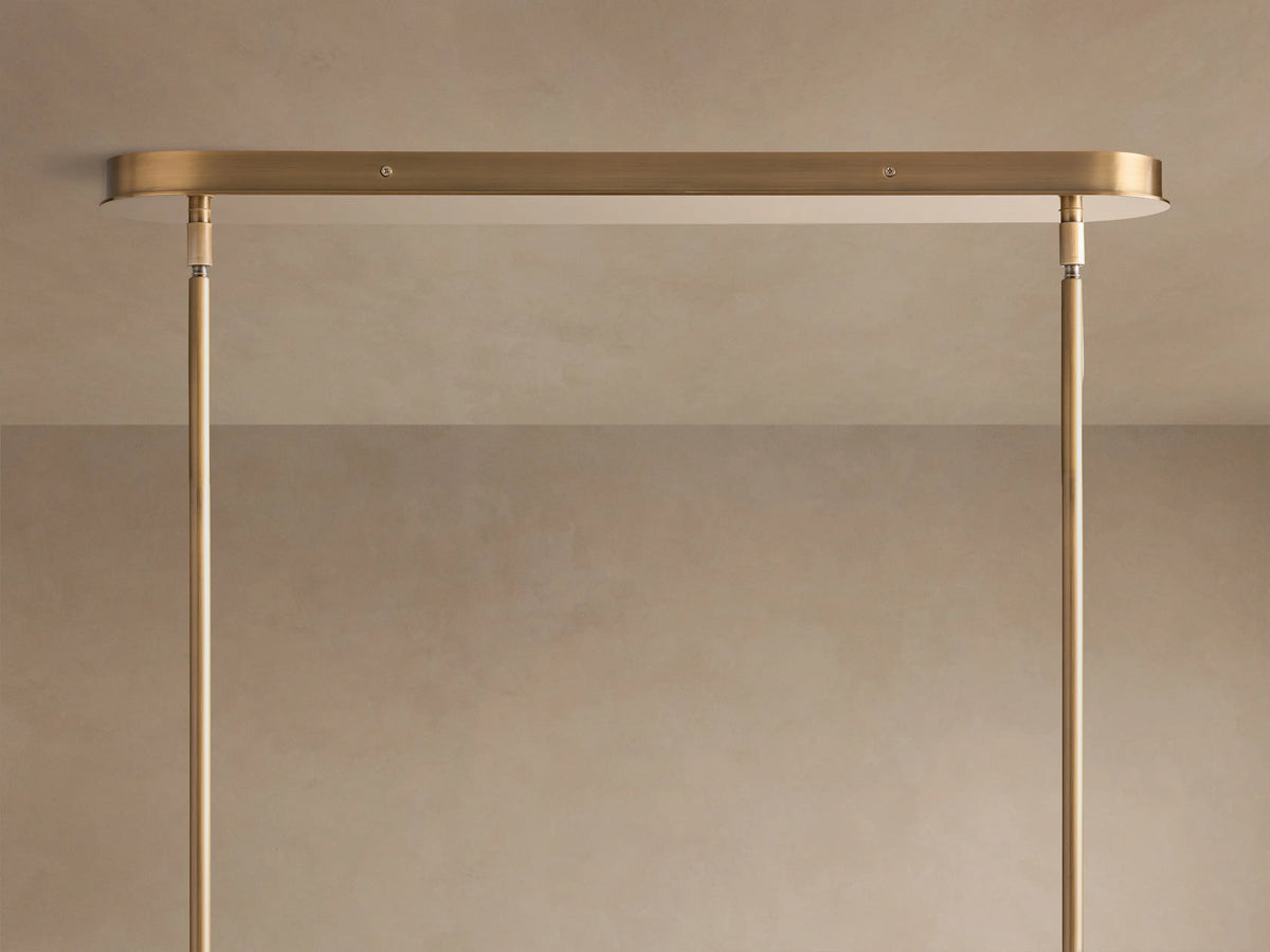 Close-up of Lyla Linear Chandelier showing illuminated milky white hand-blown glass shades with brushed brass fittings.