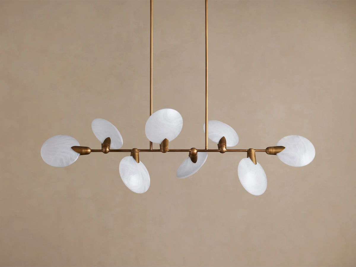 Lyla Linear Chandelier with 8 milky white oval hand-blown glass shades on an aged brass horizontal bar, suspended by two rods.