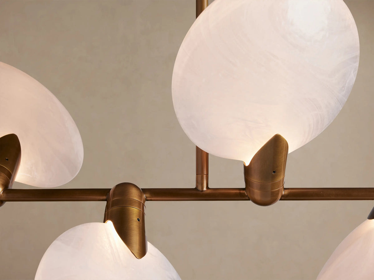 Lyla Linear Chandelier with a horizontal brass frame holding 8 milky white hand-blown glass shades, suspended by two rods.