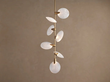 Lyla Pendant: 7 round, swirled hand-blown glass shades with glowing LED lights on a vertical brass stem against a brown wall.