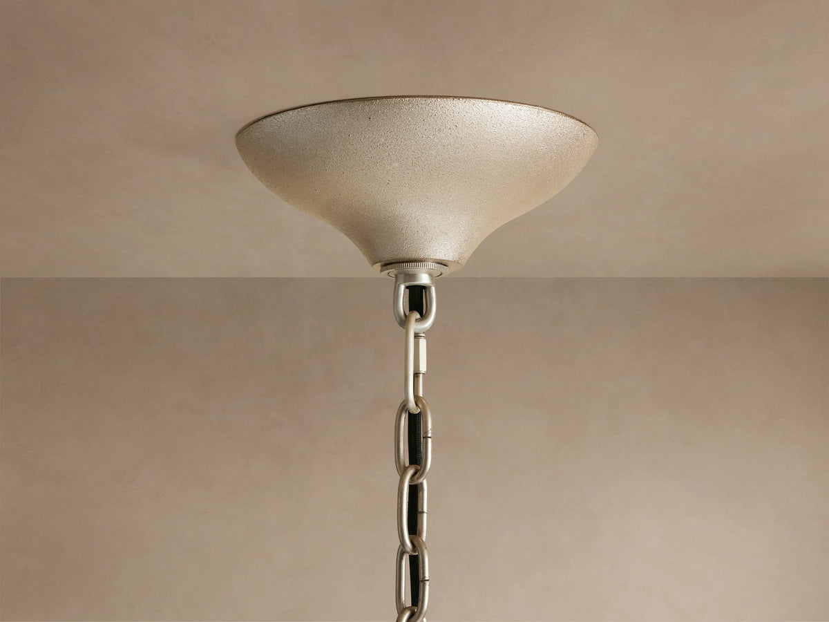 Neve Round Chandelier close-up: Champagne-finished ceiling canopy with textured surface, silver chain descends from it.