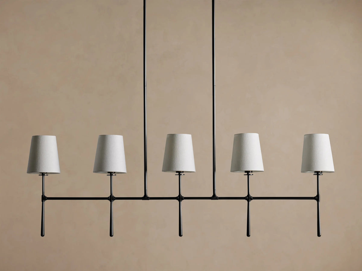 Rhodes Linear Chandelier with 5 tapered light linen shades on a dark metal horizontal bar, hanging from two rods.