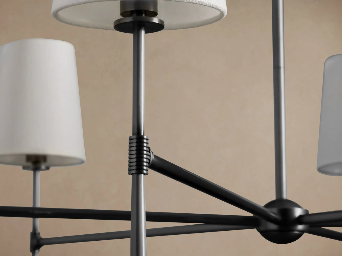 Rhodes Round Chandelier with burnished brass frame and six light linen tapered shades, suspended against a plain wall.