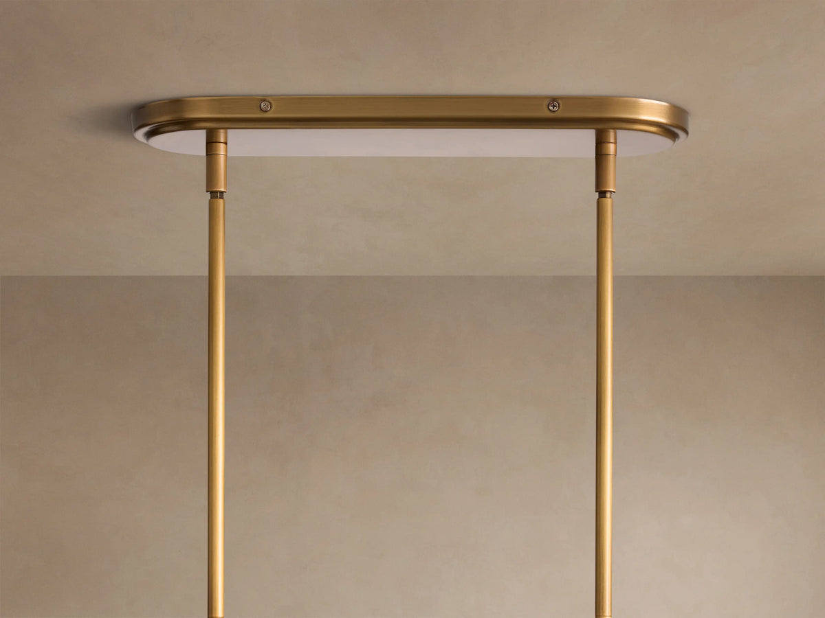 Close-up of a Rhodes Linear Chandelier showing two white tapered linen shades on a burnished brass metal frame.