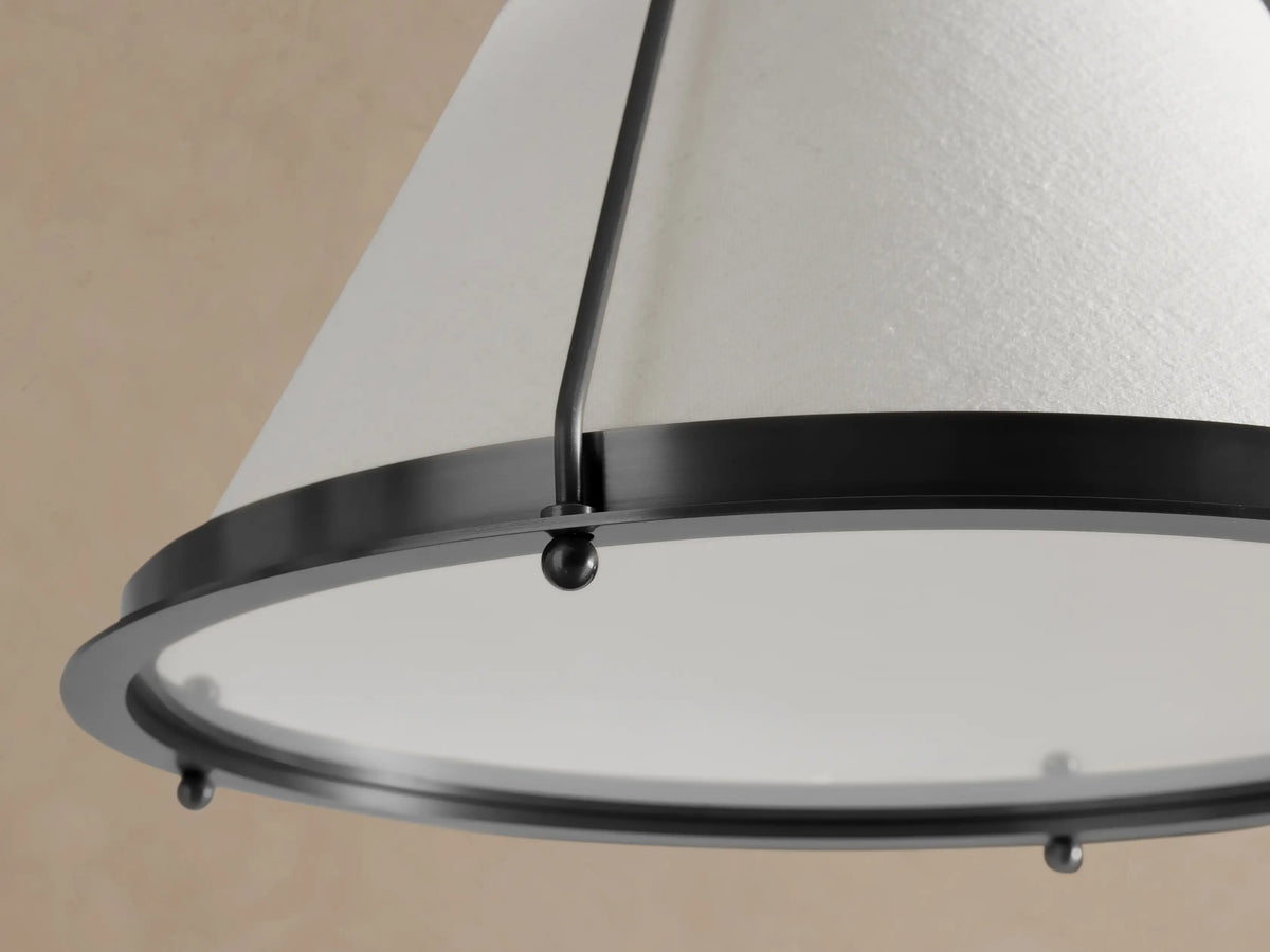 Shelton Pendant: Dark metal light with a tapered, off-white linen shade, suspended by a matching chain against a neutral wall.