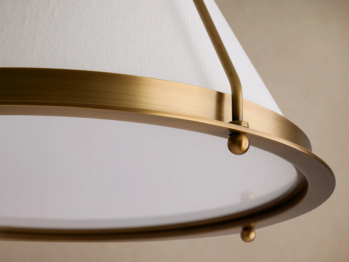 Shelton Flush Mount. Burnished brass metal frame supports a tapered off-white linen shade and clear diffuser, mounted on a ceiling.