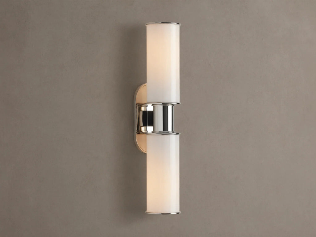 Harlin Double Sconce with two glowing vertical milk glass shades and polished nickel accents, mounted on a textured brown wall.