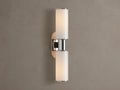 Harlin Double Sconce with two glowing vertical milk glass shades and polished nickel accents, mounted on a textured brown wall.