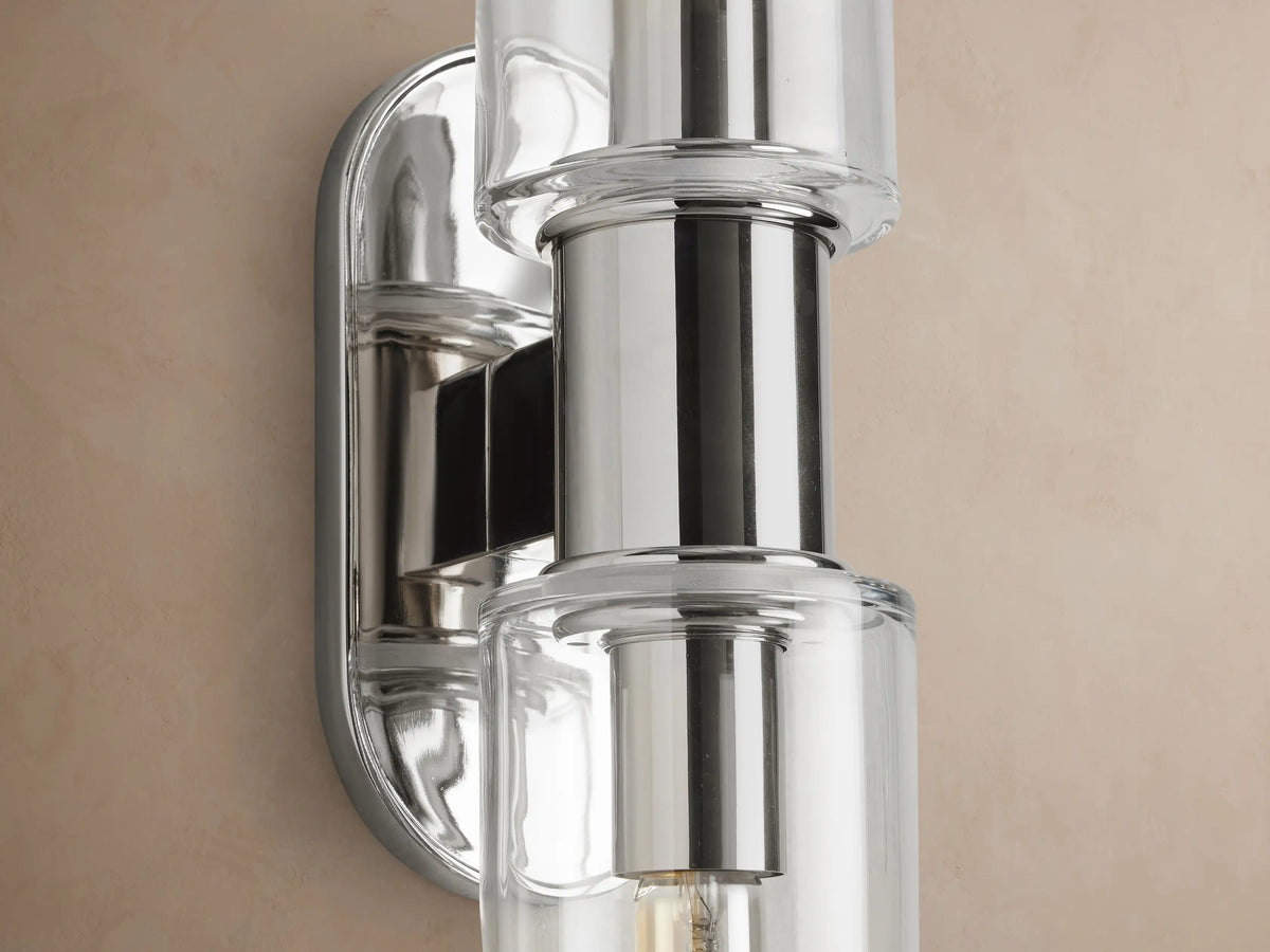 Harlin Double Sconce, polished nickel, with two vertical clear glass cloches revealing warm filament bulbs.