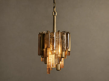 Neve Pendant, hanging, featuring a brass frame with tiered bronze cast glass panels, emitting a warm, inviting glow.