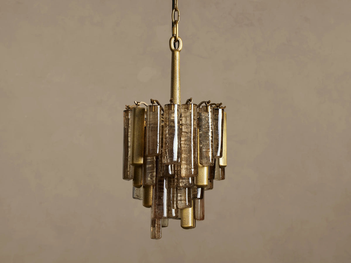 Neve Pendant, hanging, featuring a brass frame with tiered bronze cast glass panels, emitting a warm, inviting glow.