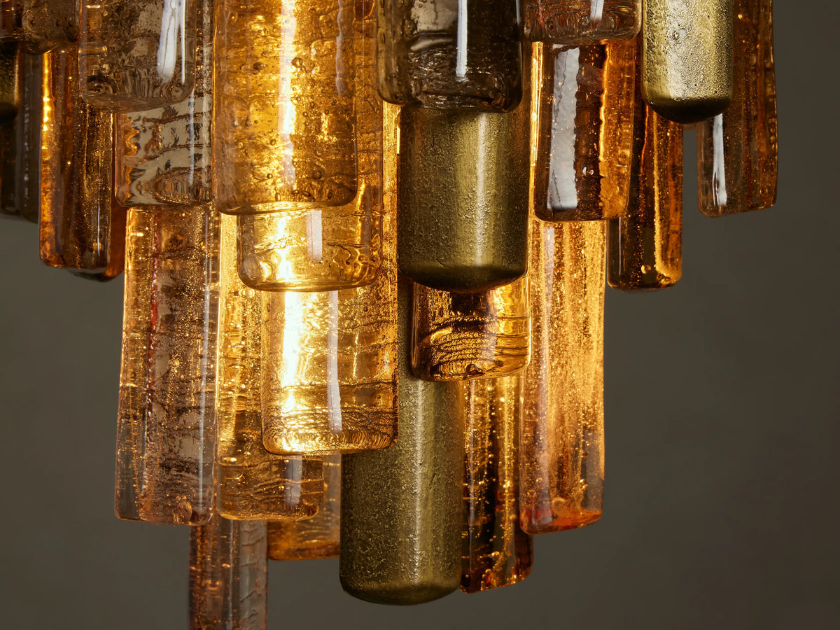 Neve Pendant: tiered chandelier with a brass-finished frame and textured bronze cast glass elements, hanging.