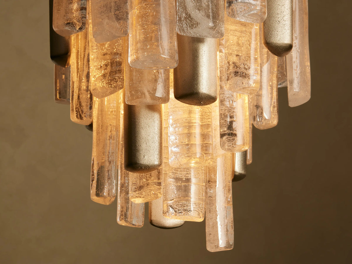 Neve Pendant: Warmly lit, textured bronze & clear cast glass cylinders hang from champagne-finish hardware.