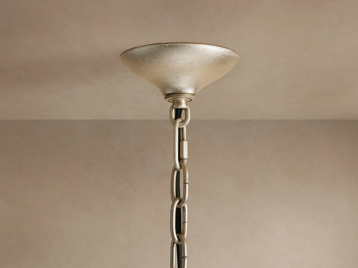 Close-up of Neve Pendant, stacked clear & bronze textured glass rods glowing warmly, interspersed with champagne/brass elements.