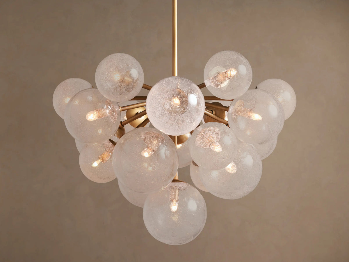 Mandoza Chandelier: Burnished brass frame holds numerous textured glass globes, each illuminated with warm light.