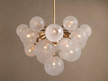 Mandoza Chandelier: Burnished brass frame holds numerous textured glass globes, each illuminated with warm light.