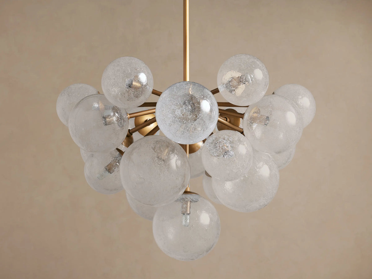 Mandoza Chandelier: Burnished brass frame holds numerous textured glass globes, each illuminated with warm light.