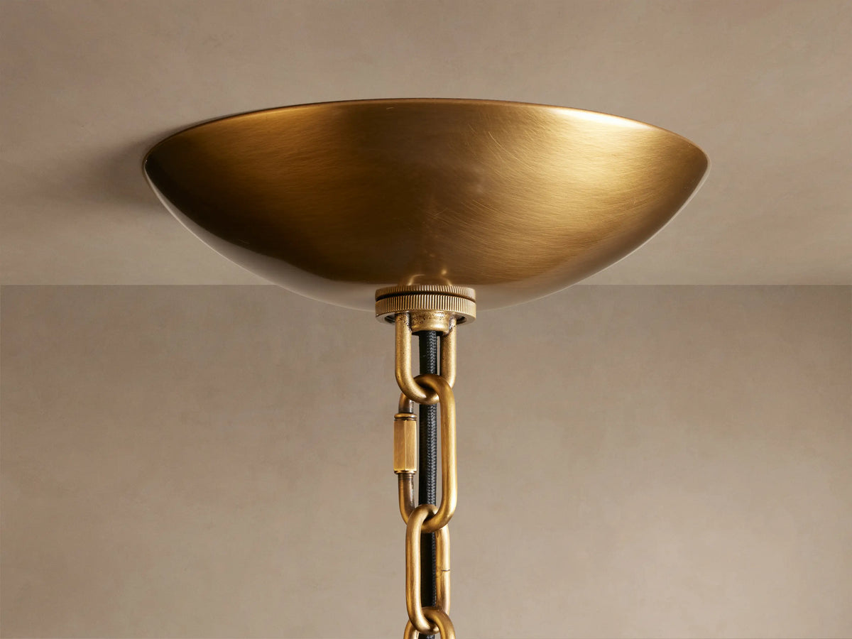 Close-up of the Blaire Round Chandelier's antique brass canopy, black fabric cord, and chain against a light ceiling.