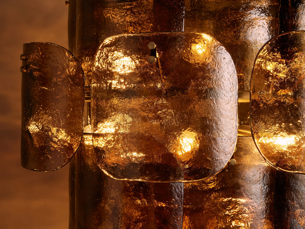 Blaire Round Chandelier with glowing pearlescent white molten glass panels showing bubbled texture, against a warm brown background.
