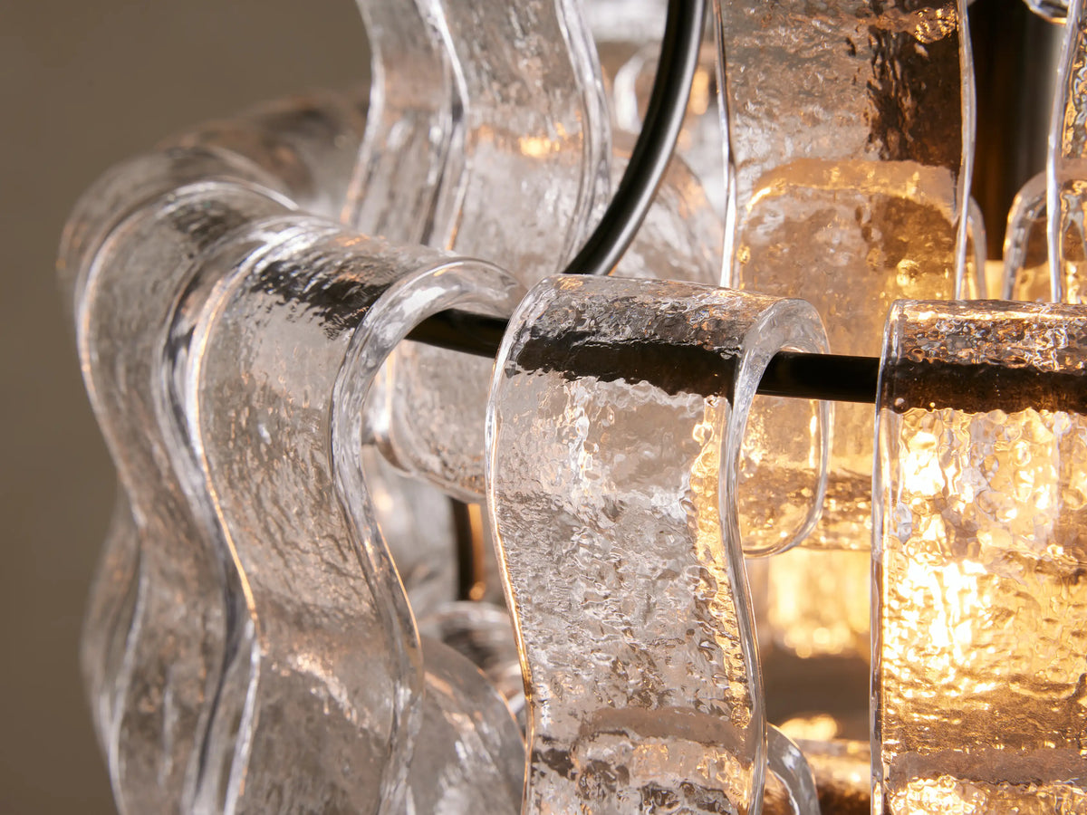 Ghiaccio Pendant with clear curved glass panels and black steel chain, suspended in front of a neutral background.