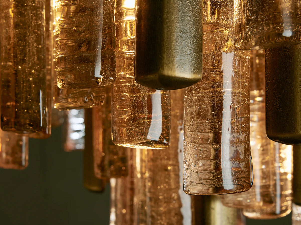 Neve Flush Mount, a tiered light fixture with champagne-finished aluminum rods and textured clear/bronze cast glass elements.
