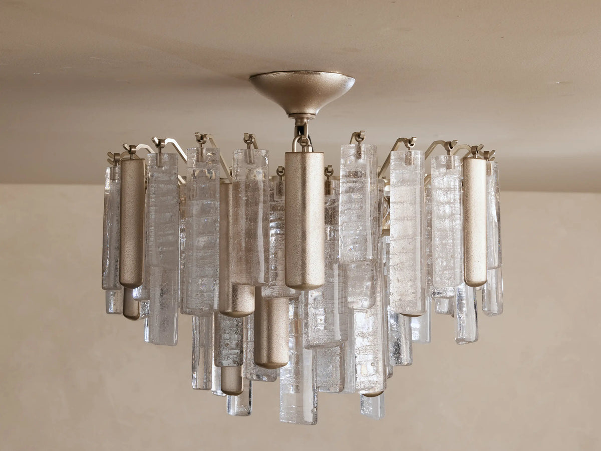 Illuminated Neve Flush Mount with champagne-finish metal base, tiered textured clear glass & metallic rods, hanging from ceiling.