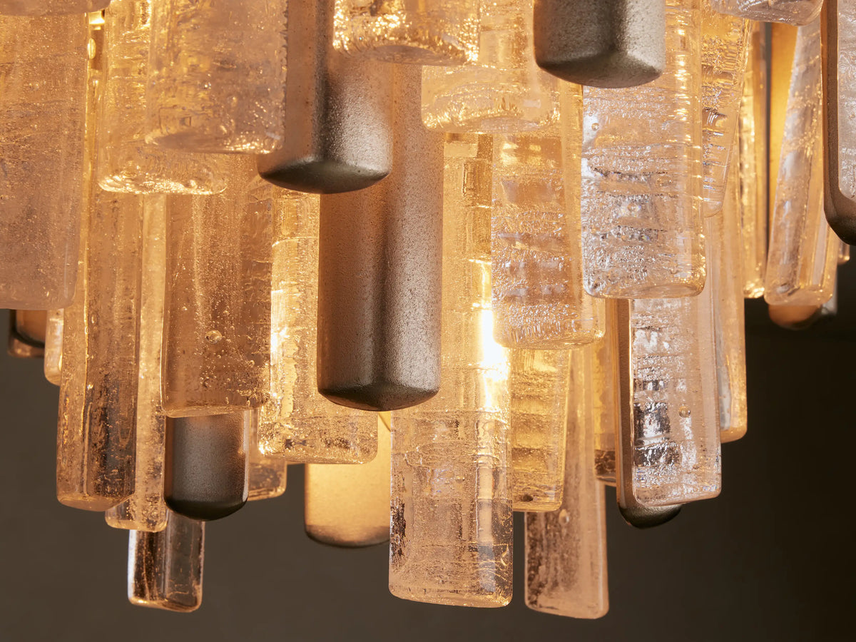Close-up Neve Flush Mount, champagne aluminum frame with illuminated, textured rectangular cast glass columns. Warm glow.