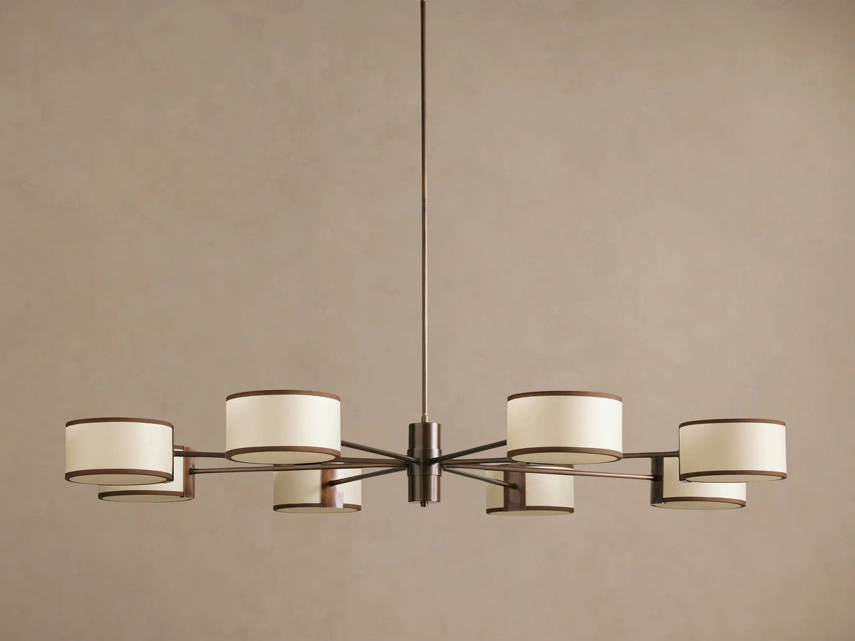 Daphne Fabric Round Chandelier with a bronze frame, 8 cream fabric drum shades with dark trim, hanging from a ceiling rod.
