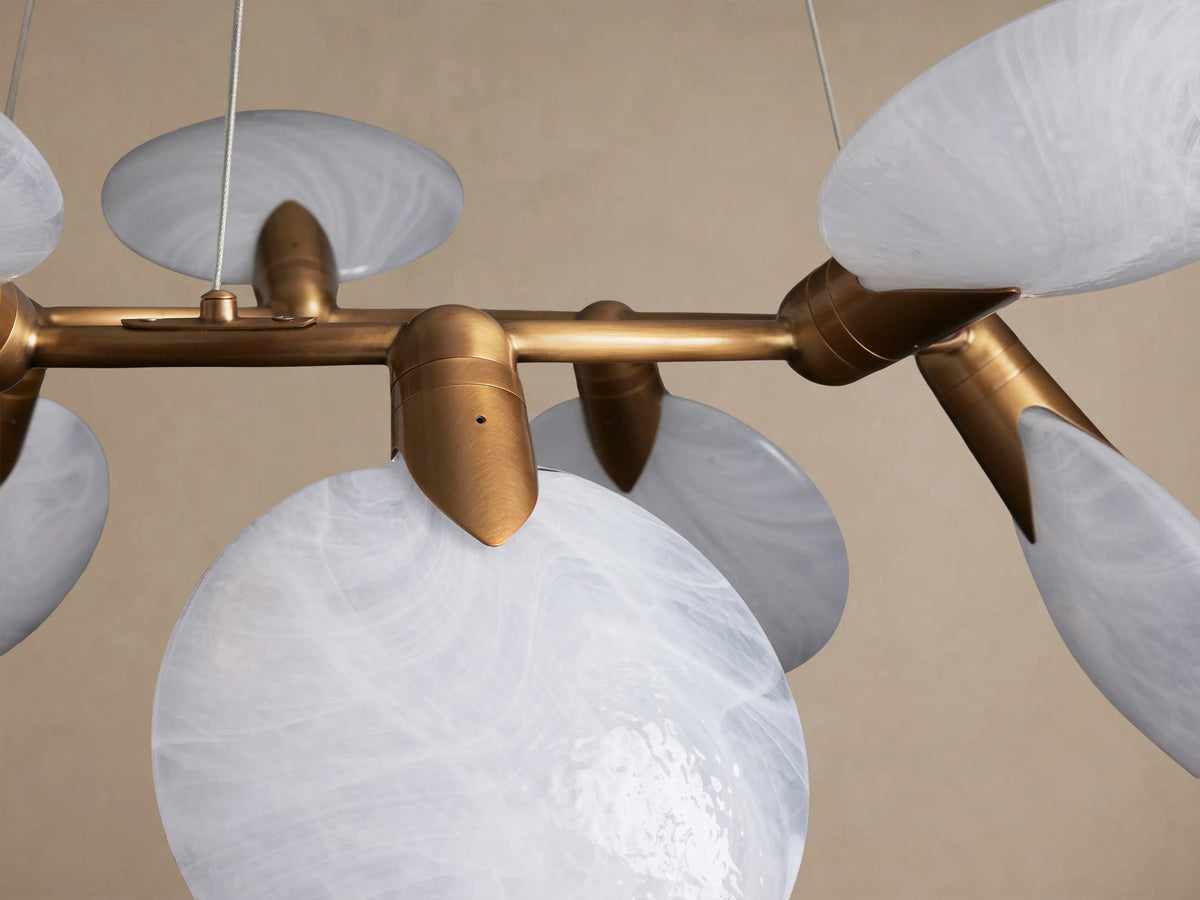 Lyla Round Chandelier: Golden brass frame holding 10 round, angled, marbled white hand-blown glass shades.