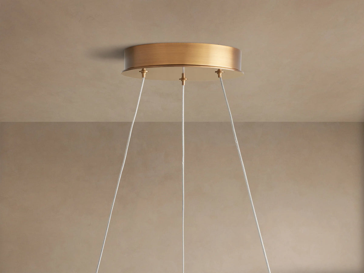 Angled close-up of Lyla Round Chandelier, showing frosted white glass shades with swirls and a textured brass frame.