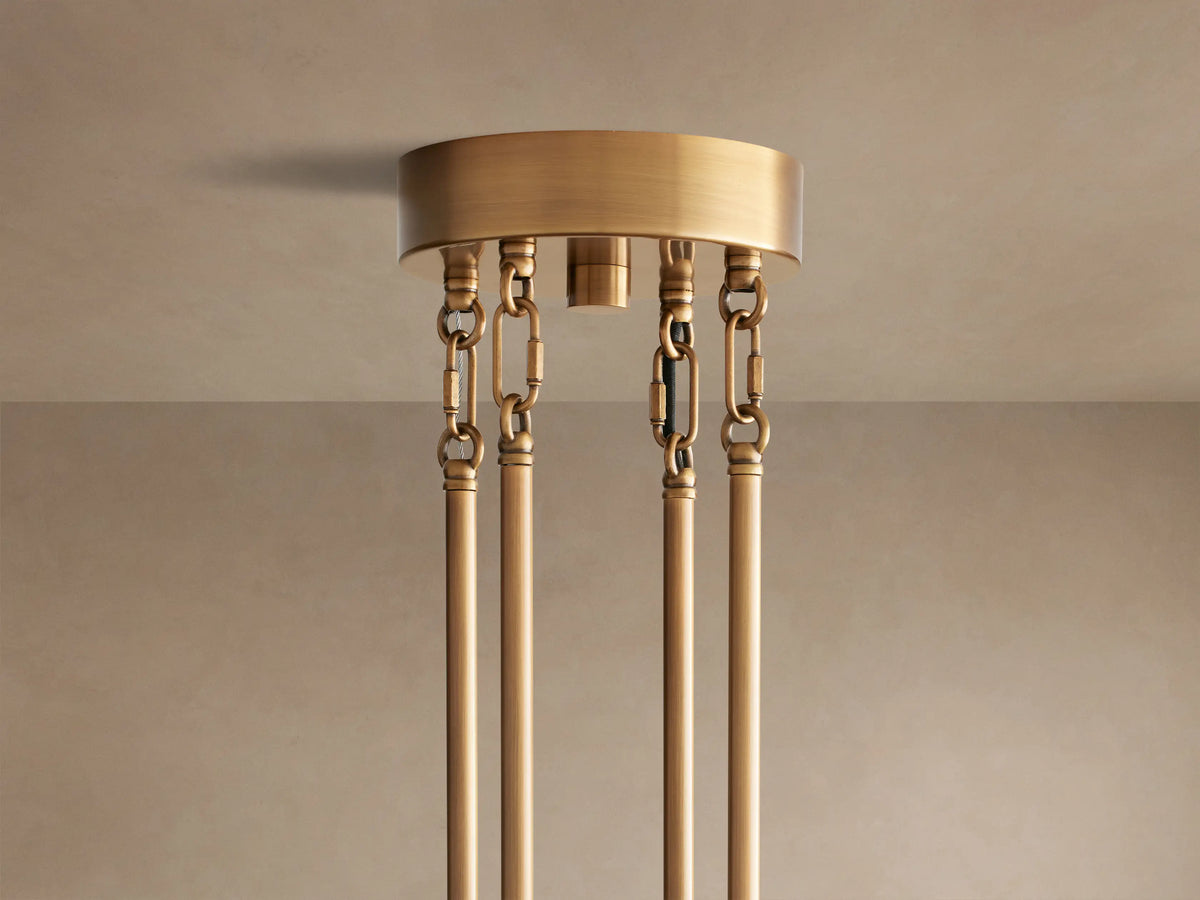 Close-up of Delsie Round Chandelier: tiered clear fluted glass rods on a burnished brass frame, reflecting light.