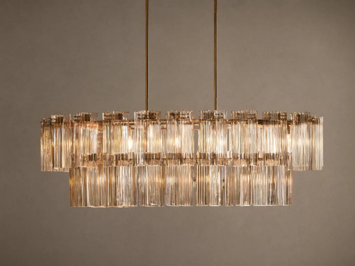 Delsie Oval Tiered Chandelier, burnished brass finish, two tiers of illuminated fluted glass rods on a simple background.