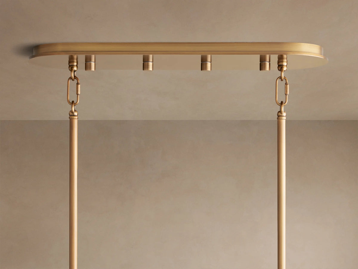 Close-up of the Delsie Oval Chandelier's burnished brass oval canopy with hanging rods against a light ceiling.