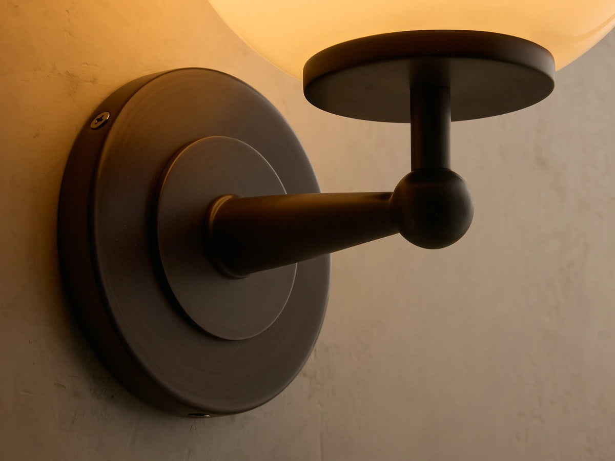 Front view of the antique bronze Fulton Sconce with a white spherical milk glass globe.