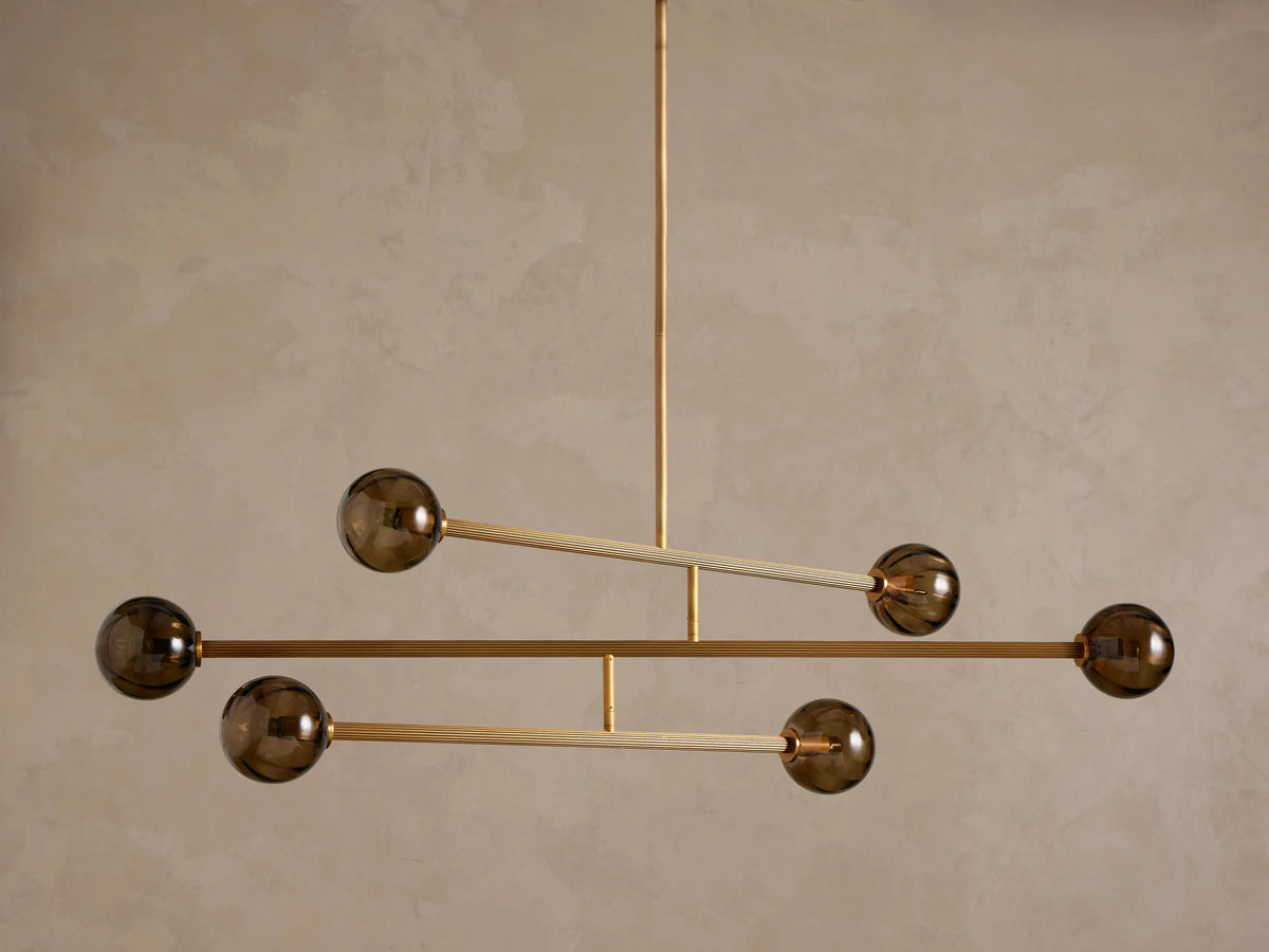 Modern chandelier with a brass frame and five smoky brown glass globe shades, suspended from above.