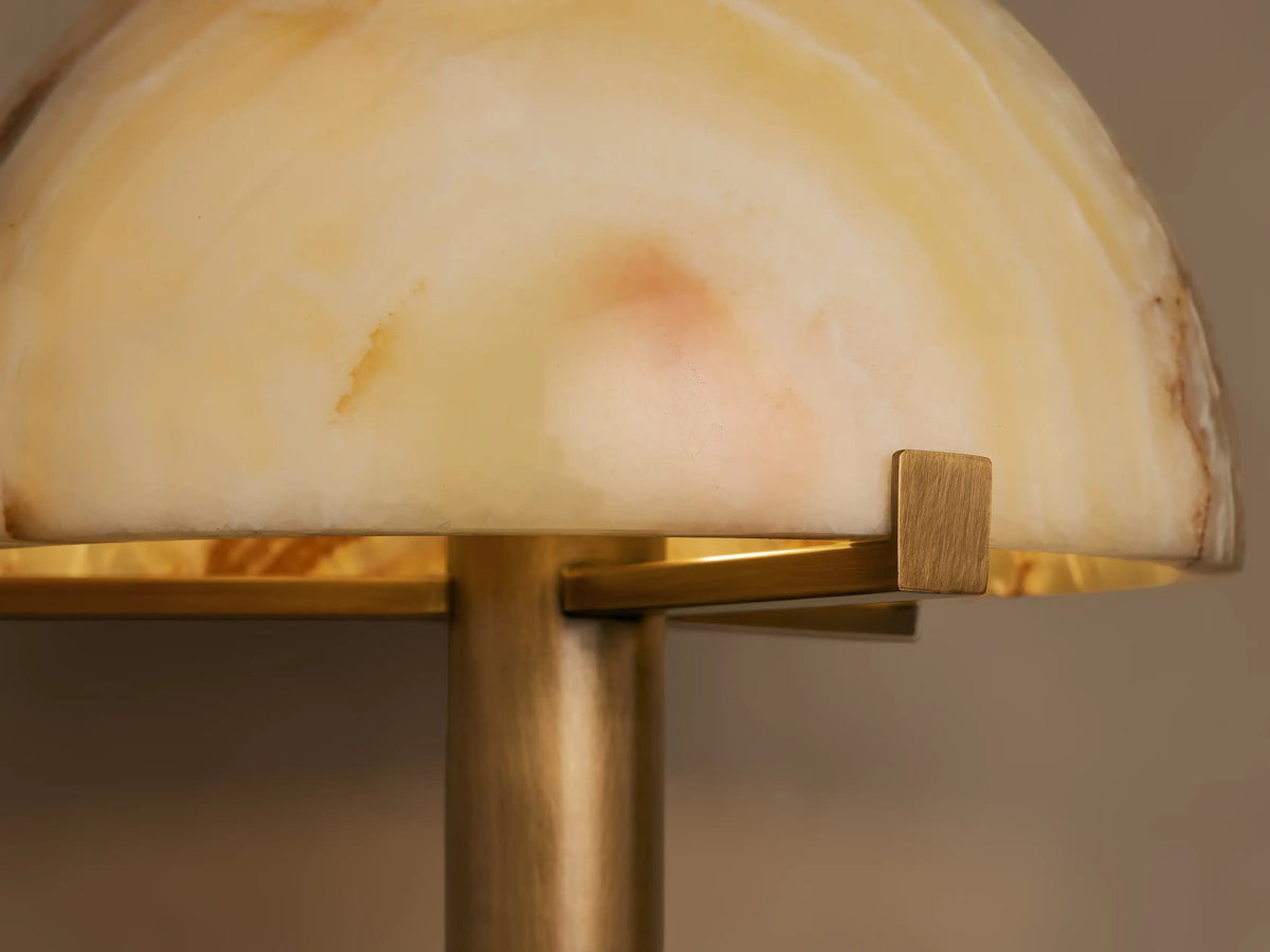 Emerie Table Lamp featuring a semicircular alabaster shade with warm hues, mounted on a sleek brass base.